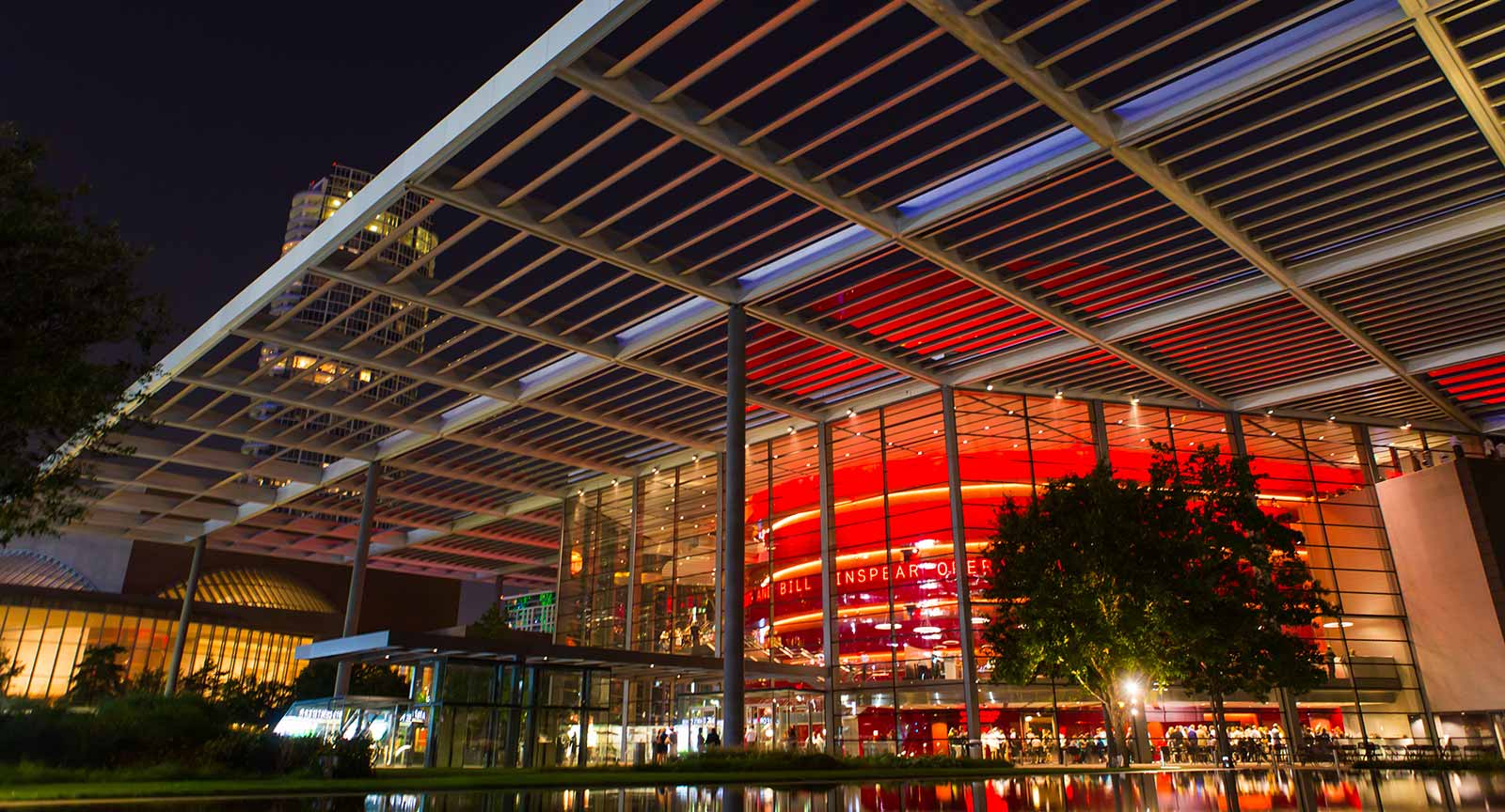 The Winspear Opera House glowing red at night under its sun canopy